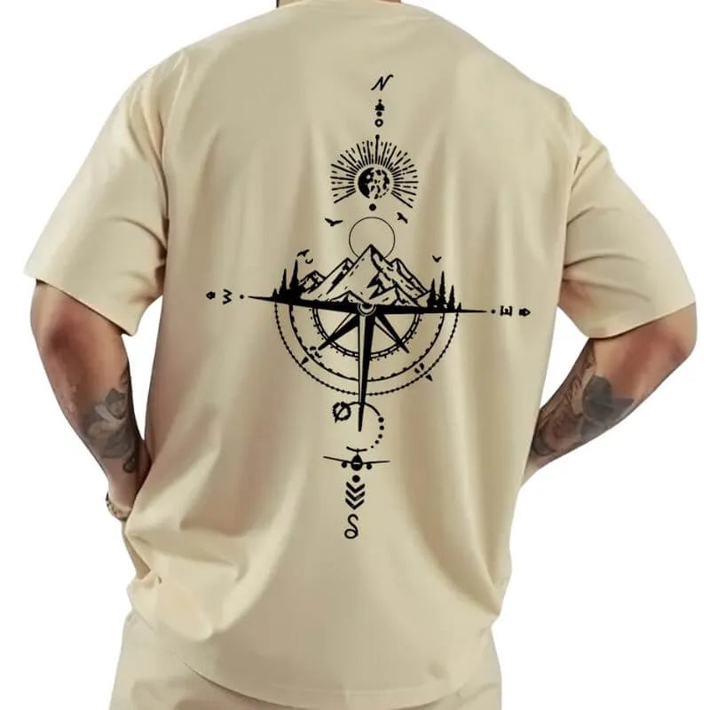 Camiseta oversized masculina bege com estampa de bússola, montanhas e avião, visual aventureiro e simbólico